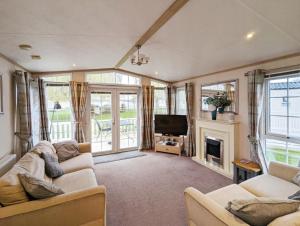 ein Wohnzimmer mit 2 Sofas und einem TV in der Unterkunft Willow Lodge in South Cerney