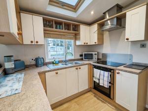 a kitchen with white cabinets and a sink at Willow Lodge in South Cerney