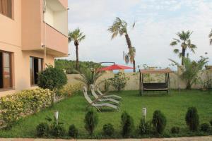 a yard with chairs and a table and palm trees at Sea in Shekvetili