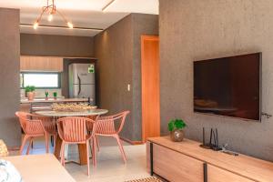 eine Küche und ein Esszimmer mit einem Tisch und einem TV in der Unterkunft KAMBY MILAGRES l Natureza e Conforto in São Miguel dos Milagres