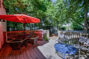 Un patio con una mesa y una sombrilla roja. en Bama Bungalow, en Tuscaloosa