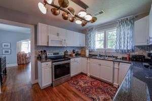 una cocina con armarios blancos y una alfombra en el suelo en Bama Bungalow, en Tuscaloosa