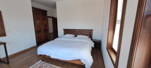 a bedroom with a bed with white sheets and a mirror at Pupa Winery Serene Stay in Berat