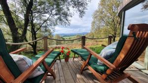 two rocking chairs sitting on a deck with a view at Luxury romantic Roundhouse and hot tub for two in Glasgow
