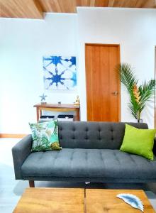 a living room with a blue couch with green pillows at Dragonfly Beach Retreat Beachfront Casitas-Adult Only in Punta Uva