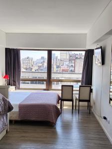 1 dormitorio con 1 cama, 2 sillas y una ventana grande en Infinit Point Apartment en Buenos Aires
