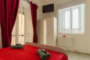 a bedroom with a red bed with two towels on it at Casta Diva Holiday Rooms in Catania