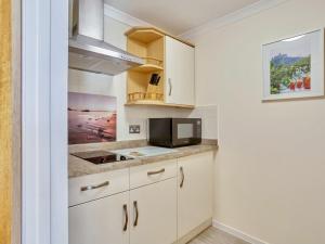 uma cozinha com armários brancos e um micro-ondas em Polgew Studio em Marazion