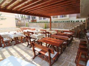 a restaurant with wooden tables and chairs in a patio at Hotel Art Media in Herceg-Novi