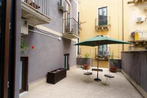 a patio with a green umbrella and chairs and a table at Casta Diva Holiday Rooms in Catania