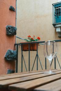 a table with a wine glass and a planter with red flowers at Casta Diva Holiday Rooms in Catania