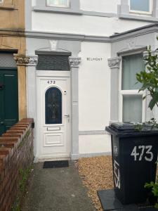 a white front door of a house with a trash can at Lovely room in Bristol 5 in Bristol