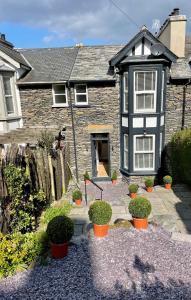 a house with potted plants in front of it at Heather Mere Cottage, Bowness-on-Windermere in Bowness-on-Windermere