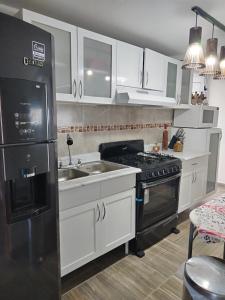 La cuisine est équipée de placards blancs et d'un réfrigérateur noir. dans l'établissement Casa 2 recámaras, à Mexico