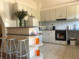 a kitchen with white cabinets and a counter with stools at Nysa8 in Paphos
