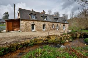 Stary kamienny dom z potokiem przed nim w obiekcie Gîte du moulin vert w mieście Plounevez-Moëdec