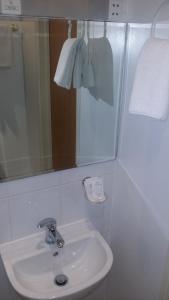 Baño blanco con lavabo y espejo en Arriva Hotel en Londres