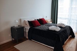 a bedroom with a large black bed with red pillows at Šventoji Elija in Palanga