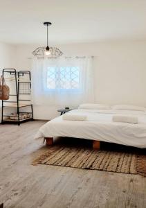 a white bedroom with a large bed and a window at bloom in Eilat