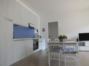 una cucina con armadi bianchi, tavolo e sedie di Lake Como Casa la Rosa apartment Iris ad Abbadia Lariana