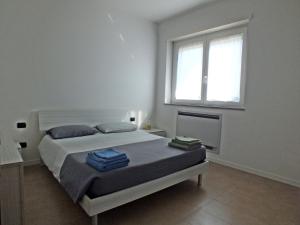 a white bedroom with a bed and a window at Lake Como Casa la Rosa apartment Iris in Abbadia Lariana