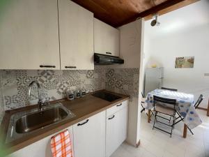 uma cozinha com armários brancos, um lavatório e uma mesa em La Casetta di Rosanna - Stintino em Stintino