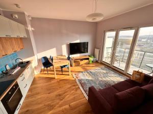 a kitchen and living room with a couch and a tv at 16 Floor nad morzem - prawy in Gdańsk