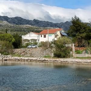 a house with a car parked next to a river at Paklenica Sport Apartments in Starigrad