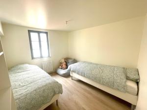 a bedroom with two beds and a teddy bear sitting on the floor at Charmant logement rénové dans l’hyper centre in Auxerre