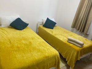 two beds with yellow covers in a room at Peaceful Hills Self Catering Holiday House in Lusaka