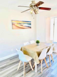 a dining room table with white chairs and a ceiling fan at Beautiful home near Disneyland. Entire place! in Orange