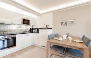 a white kitchen with a wooden table and chairs at Prince in Binz +34 photos