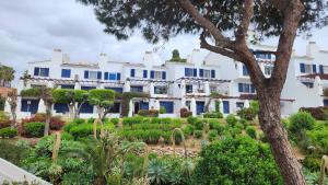 a large white building with blue windows and a garden at ELENA flat A little paradise right on the BEACH in Sitio de Calahonda