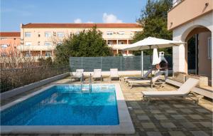 uma piscina com cadeiras e um guarda-sol ao lado de um edifício em Lovely Home In Pula With Swimming Pool em Pula
