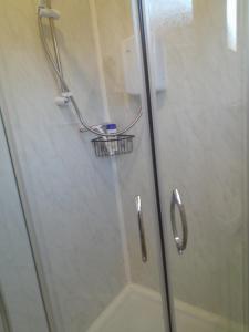 La salle de bains est pourvue d'une douche avec une porte en verre. dans l'établissement Perfect chalet to relax in k4, à Mablethorpe