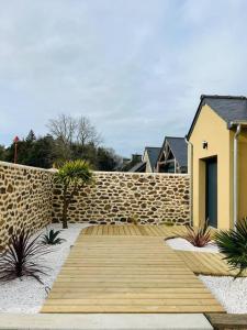 una pasarela de madera frente a una pared de piedra en Maison Terracotta vous accueille à 8min de Dinard, en Le Minihic-sur-Rance