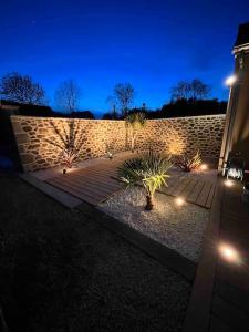 a stone wall with plants in a courtyard at night at Maison Terracotta vous accueille à 8min de Dinard in Le Minihic-sur-Rance