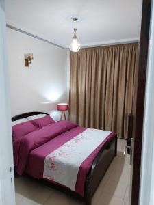 een slaapkamer met een bed met paarse lakens en een raam bij harmony house 2 in Rabat