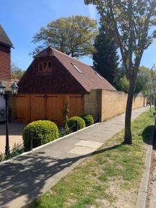 a house with a fence and a tree and a sidewalk at Little Barn ideal for short stays in Bexley