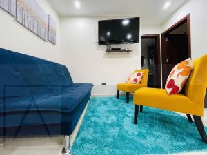 - un salon avec un canapé bleu et deux fauteuils jaunes dans l'établissement Yovanna Elegante Apartamento 1 dormitorio, à Santa Cruz de la Sierra