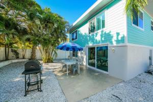 um pátio com uma mesa, um guarda-chuva e um grelhador em The Mahi em Siesta Key