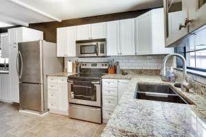 una cocina con armarios blancos y electrodomésticos de acero inoxidable en Updated Buffalo Springs House on the Lake!, 