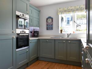 a kitchen with blue cabinets and a clock on the wall at Blue Haven in Westward Ho