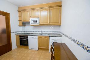 a kitchen with wooden cabinets and a white dishwasher at Apartamento Paco entre Valencia y Castellón in Benafer