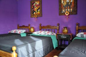 duas camas num quarto com paredes roxas em Hostel Copacabana La Quiaca em La Quiaca