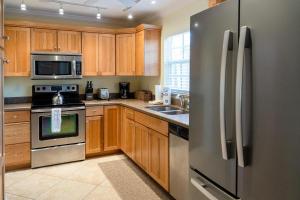 uma cozinha com armários de madeira e um frigorífico de aço inoxidável em Royal Palm #1B em Siesta Key