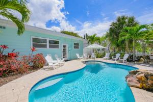 a swimming pool with chairs and a house at Beach Side Babe in Sarasota