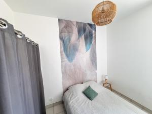 a small bedroom with a bed and a painting on the wall at A 200m de la plage - L'Océan - in Mimizan-Plage