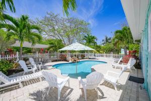 a patio with white chairs and a swimming pool at Beach Side Babe in Sarasota
