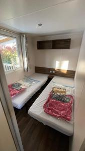 2 camas en una habitación pequeña con ventana en Mobil home Onesse et Laharie RML Newcamp "le bois des Landes", en Onesse-et-Laharie